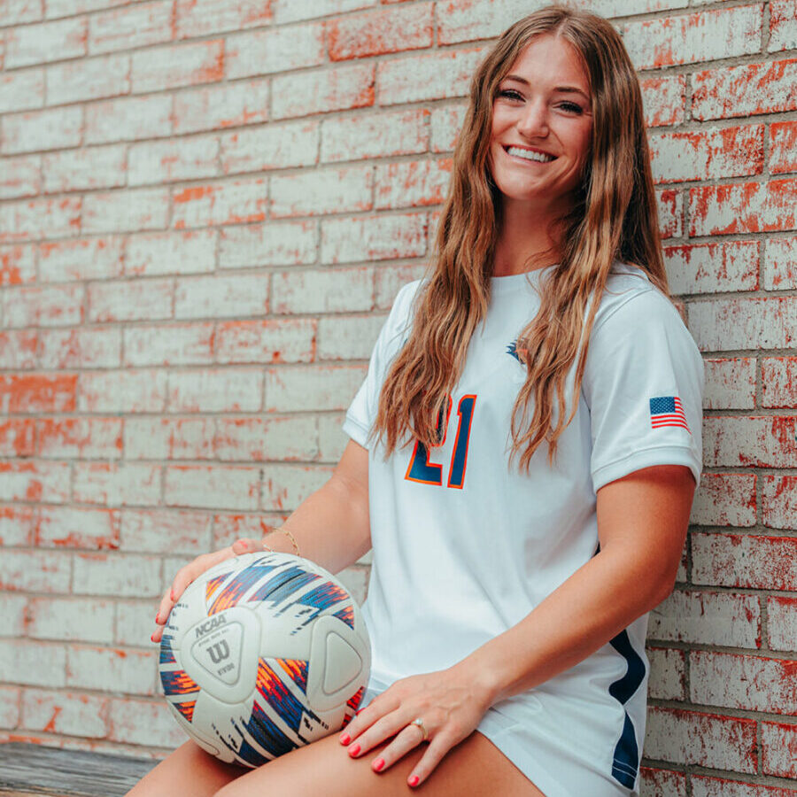 Rylee Miller sitting with a soccer ball on her lap.