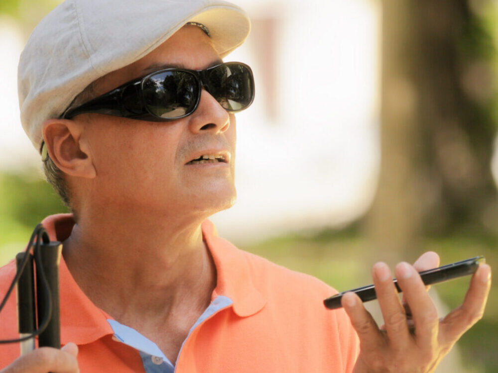 Blind man using a cellphone for digital assistance.