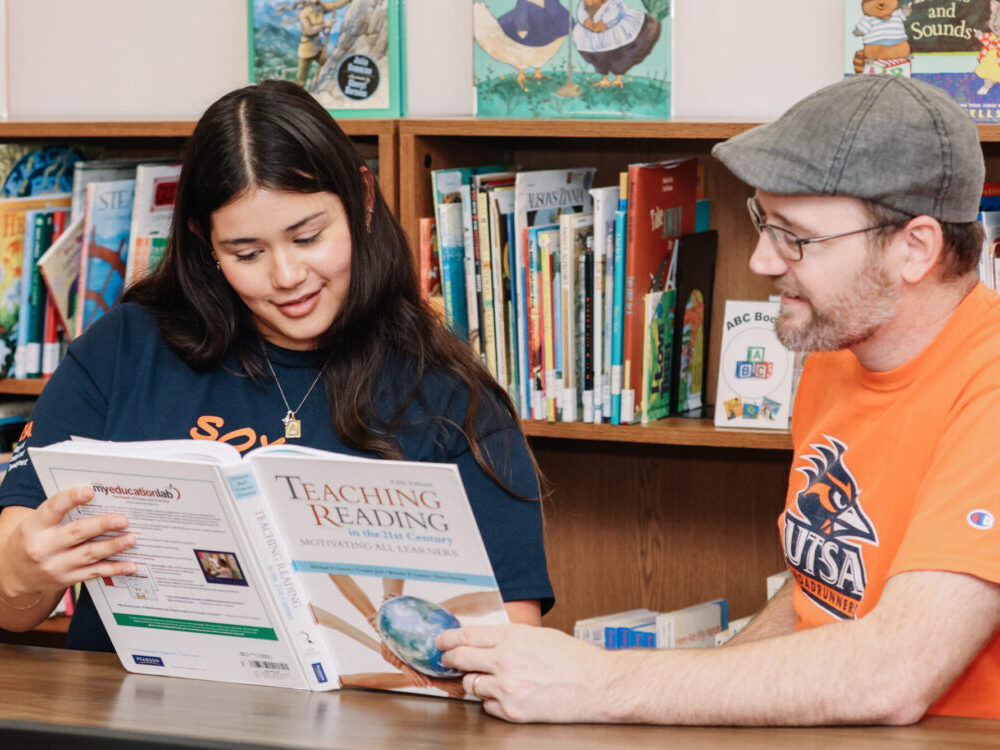 A teacher and student looking through a book together.