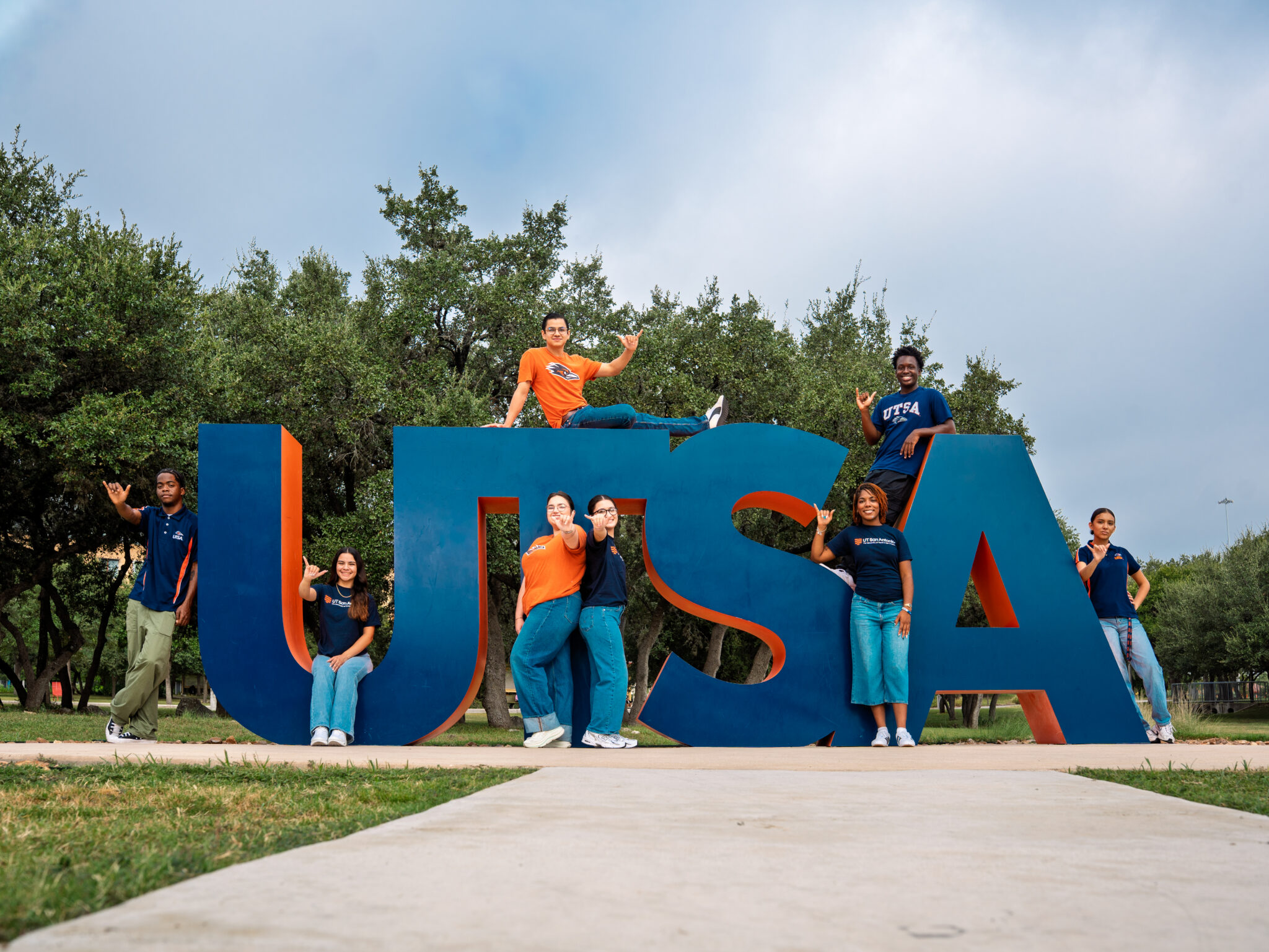 A group of student mentors posing in front of large "UTSA" signage.