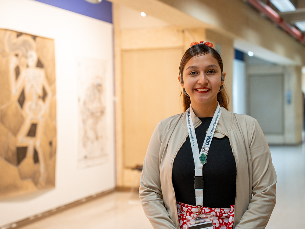 UTSA Student standing in front of art exhibit