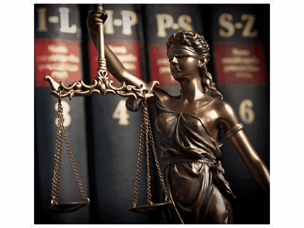 A statue of lady justice holding balancing scales in front of a shelf of books