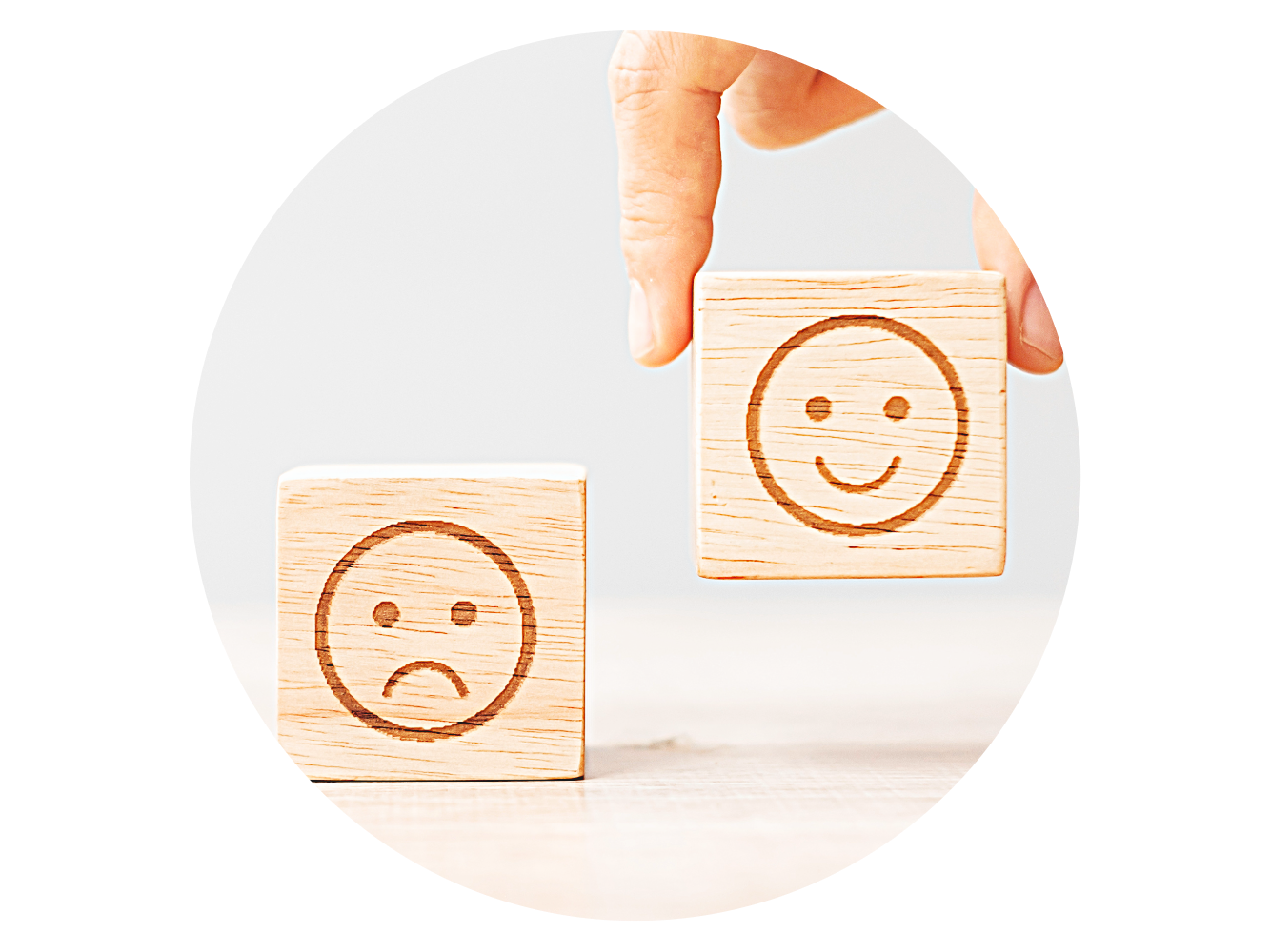 two wooden blocks one with a frowning face and one with a smiling face