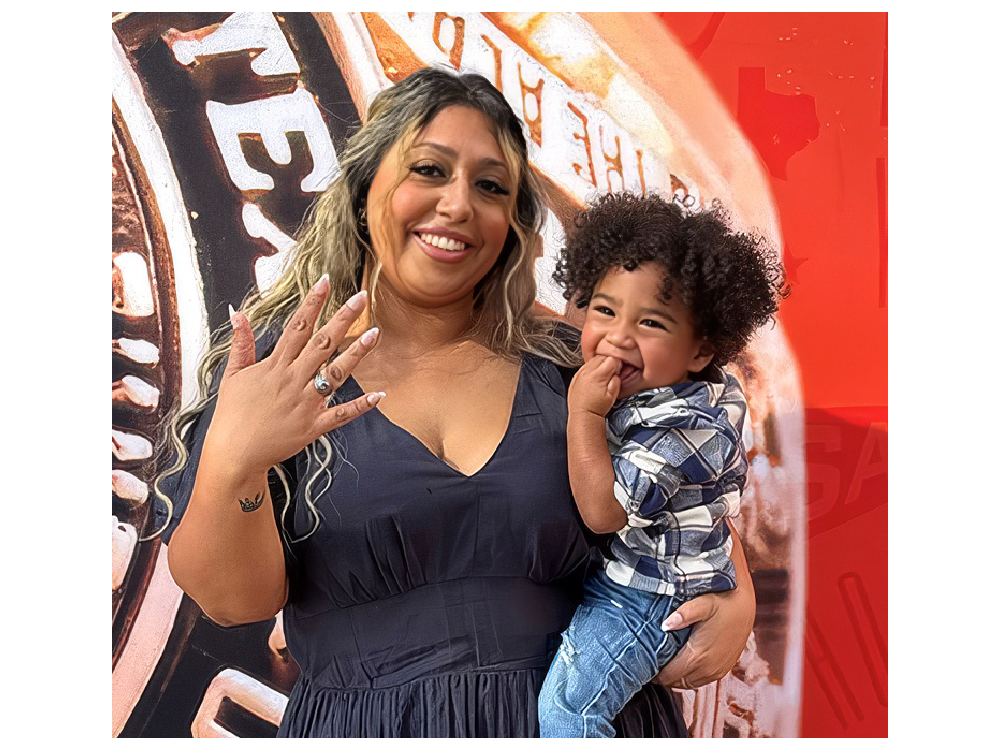 Sophia Kayani holding her son and posing with her class ring.