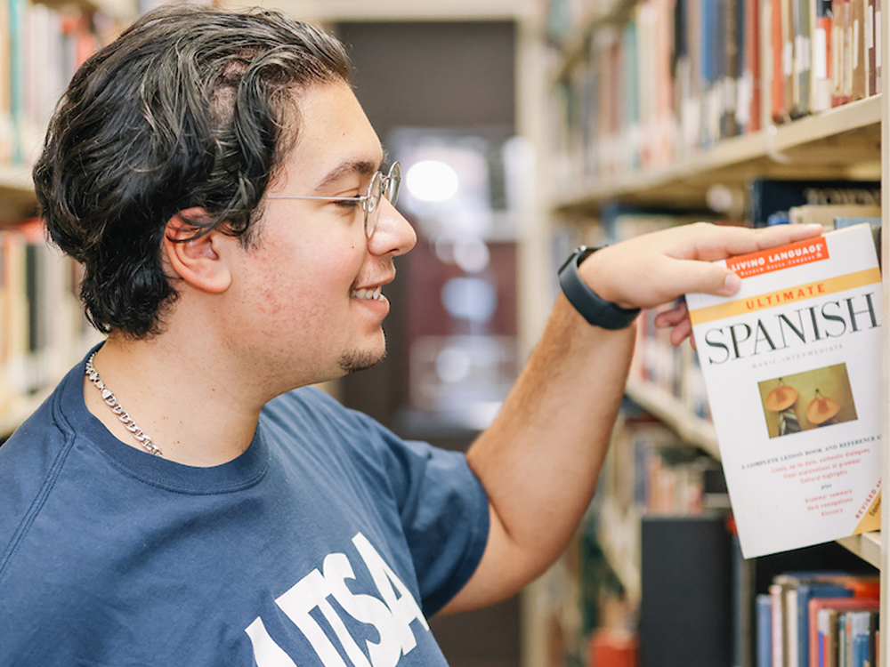 History student looking at Spanish book in library