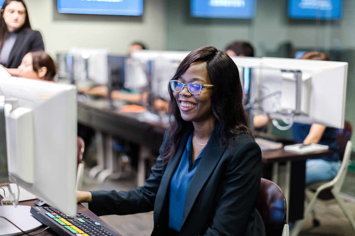UT San Antonio College of Business Student smiling while working on a computer in class