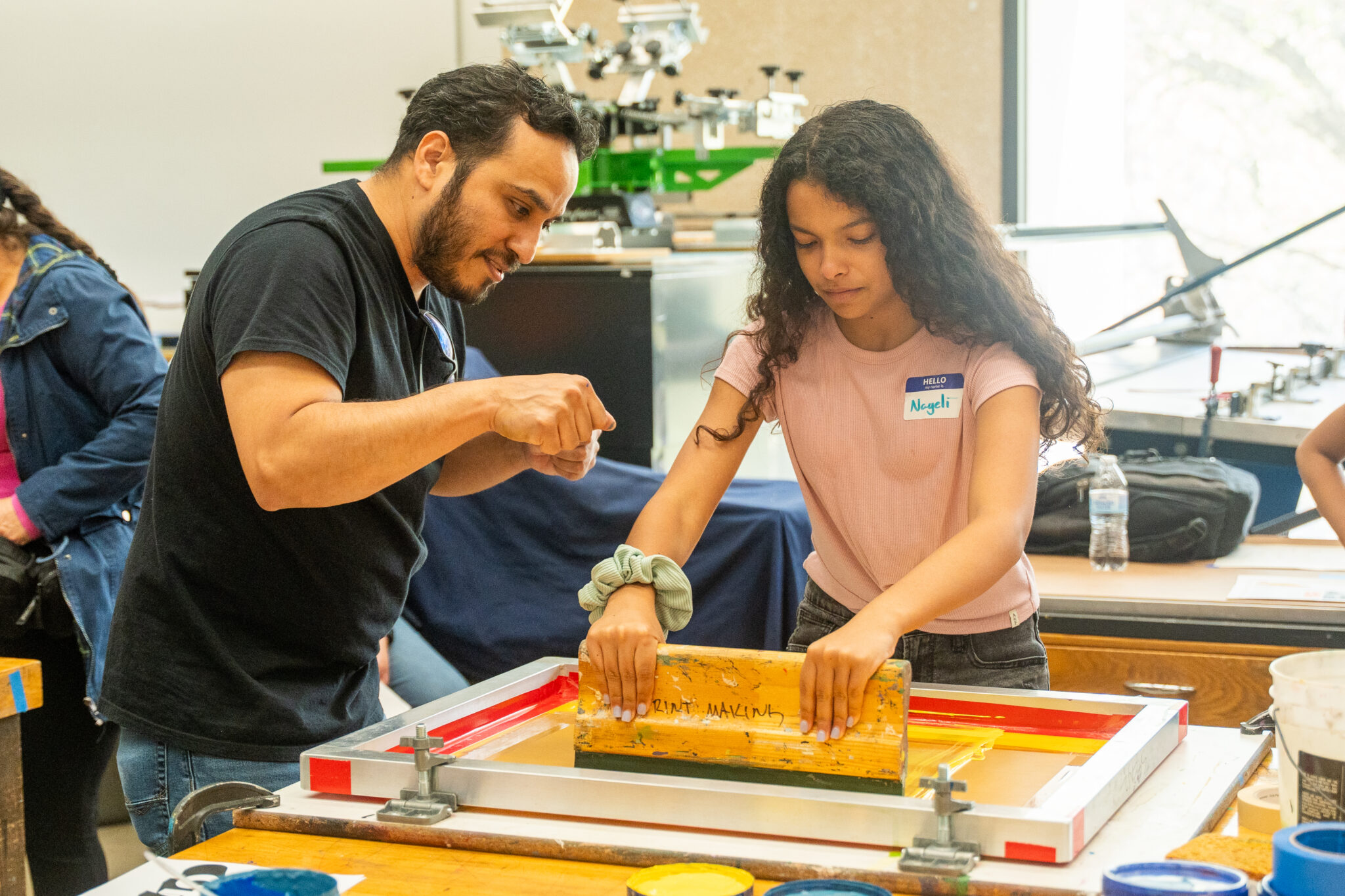Art professor assisting a child with their own print making project.