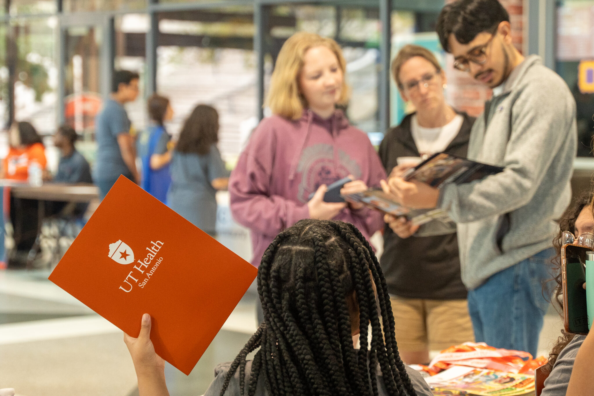 A child holds a UT Health folder while adults are in conversation.