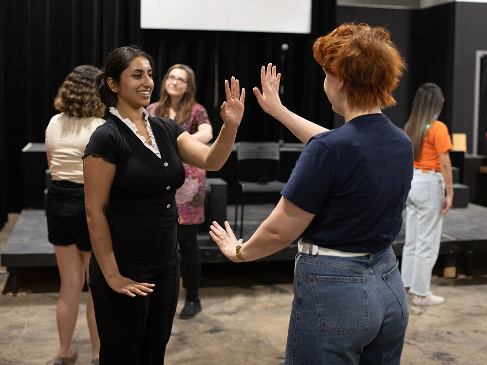 Theater members doing a mirroring exercise back stage.