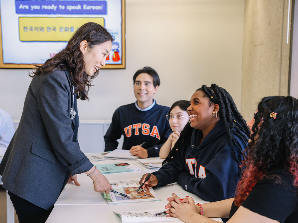 A group of three students and their Korean teacher studying the language.