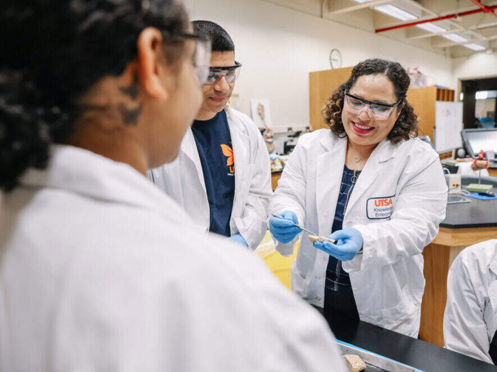 Biology professor analyzing a specimen in a lab with students.