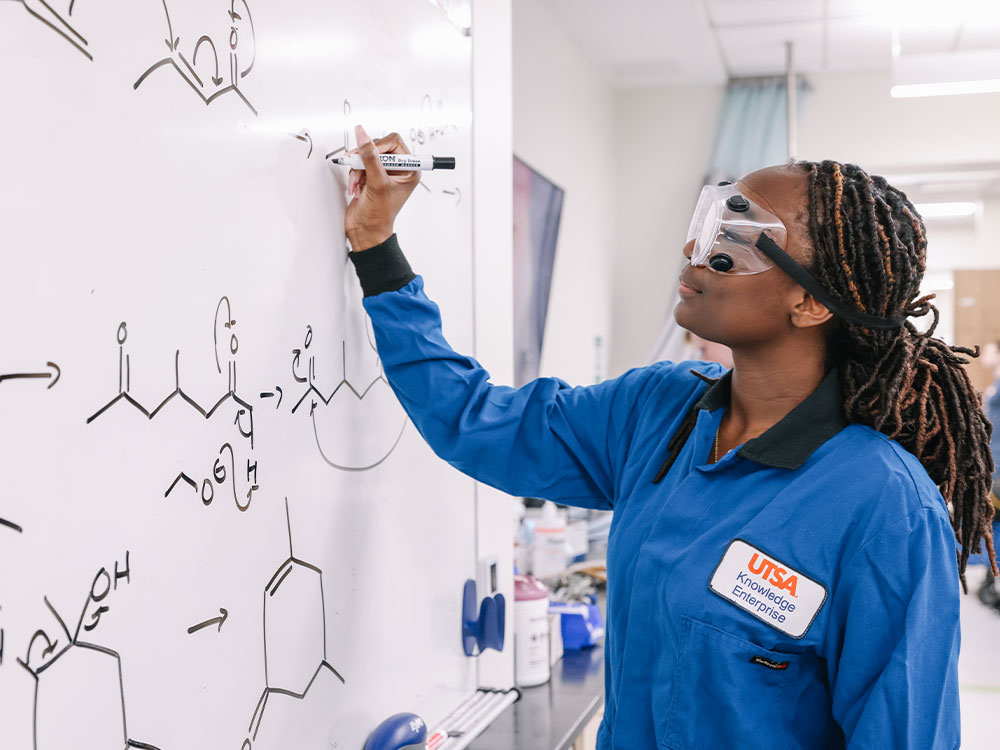 Chemistry student at UTSA writing on whiteboard in lab