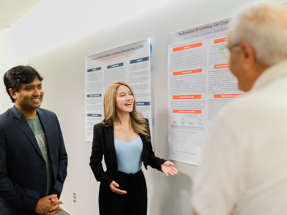 Two doctoral students presenting their research in a conference format.
