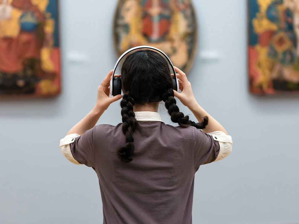 Young woman in a museum using headphones to interact with an exhibit.