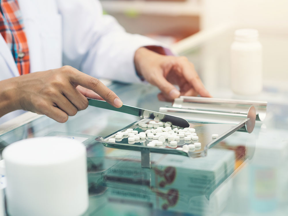 Pharmacist counting medicine on a counter.