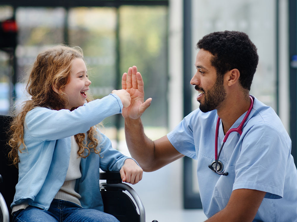 Medical professional giving a young patient a high five.